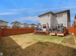 Spacious backyard featuring a multi-level wood deck with glass panel railing - 