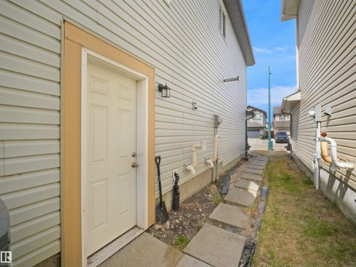 Cream-paneled exterior door with contrasting trim, complemented by an exterior wall sconce - 3247 15 Avenue Nw, Edmonton, AB 