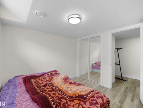 Room featuring light wood-finish flooring, a flush-mount ceiling light, and a closet with mirrored sliding doors - 3247 15 Avenue Nw, Edmonton, AB 