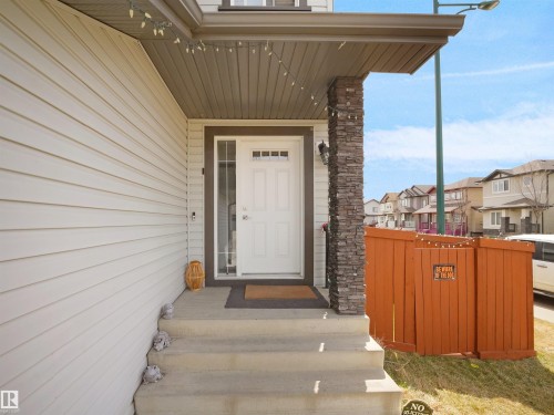Exterior entry featuring white siding and a stone-clad porch pillar - 3247 15 Avenue Nw, Edmonton, AB 
