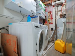 Laundry area featuring a side-by-side washer and dryer, a water heater, and exposed utility lines - 