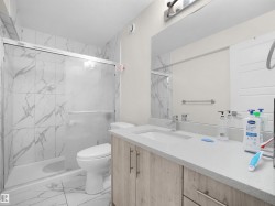 Bathroom featuring a single vanity with wood-finish cabinetry, a stone-finish countertop, and a built-in sink - 