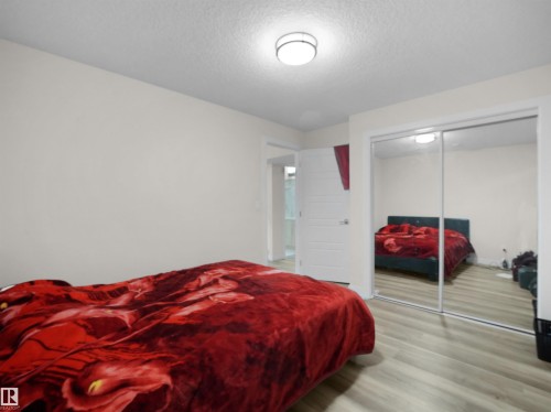 Bedroom featuring light-toned wood-finish flooring and a flat-panel door - 3247 15 Avenue Nw, Edmonton, AB 