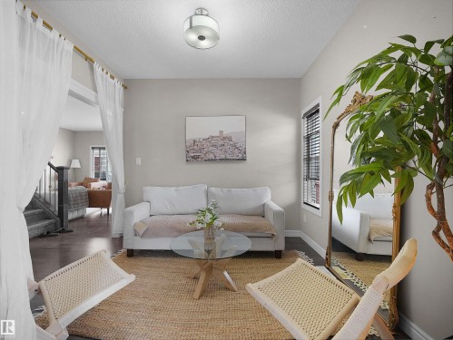 Living area featuring wood-finish flooring, light grey wall paint, and a semi-flush mount ceiling light - 3247 15 Avenue Nw, Edmonton, AB 