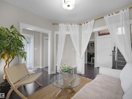 Open concept living space featuring dark wood-finish flooring, light gray wall tones, white trim, and a contemporary ceiling light fixture - 3247 15 Avenue Nw, Edmonton, AB 