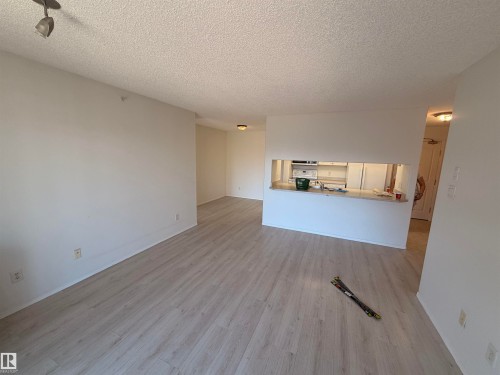 Open living area featuring light wood-finish flooring, white painted walls, and textured ceilings - 424 16303 95 Street, Edmonton, AB - Indoor Photo Showing Other Room