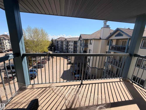 Balcony with metal railing and concrete flooring, overlooking residential buildings with pitched shingle roofs - 424 16303 95 Street, Edmonton, AB - Outdoor With Balcony With Exterior
