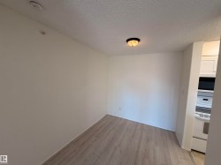 Bright interior space featuring light-toned wood-finish flooring, white walls, and a ceiling-mounted light fixture - 