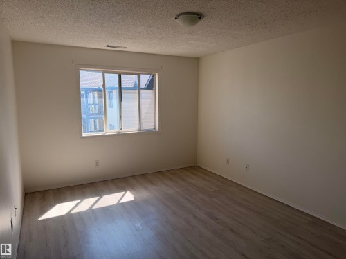 Bright room featuring a window with white trim, wood-finish flooring, a neutral color palette, and a flush-mount ceiling light fixture - 424 16303 95 Street, Edmonton, AB - Indoor Photo Showing Other Room