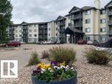 Multi-story apartment building featuring a covered entryway, individual balconies, and a paved parking lot - 424 16303 95 Street, Edmonton, AB  - Outdoor With Balcony With Facade 