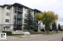 Multi-story condominium building featuring light-colored siding with dark trim accents - 424 16303 95 Street, Edmonton, AB  - Outdoor With Balcony 