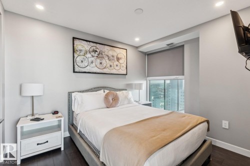 Bedroom featuring dark wood-finish flooring, recessed lighting, and a window with a roller shade - 3302 10180 103 Street, Edmonton, AB - Indoor Photo Showing Bedroom