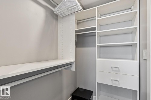 Custom closet organization system featuring white shelving, hanging rods, and integrated drawers with contemporary pulls - 3302 10180 103 Street, Edmonton, AB - Indoor With Storage