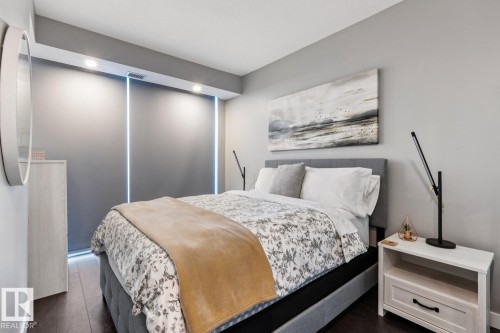 Recessed lighting illuminates this room featuring dark wood-finish flooring, light gray walls, and a built-in window treatment - 3302 10180 103 Street, Edmonton, AB - Indoor Photo Showing Bedroom