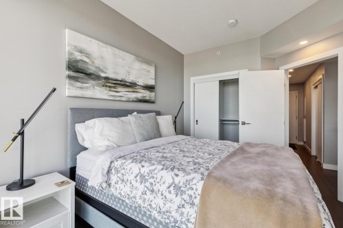 Bedroom featuring light gray wall paint, wood-finish flooring, a built-in closet with sliding doors, and a door to an interior hallway - 3302 10180 103 Street, Edmonton, AB - Indoor Photo Showing Bedroom