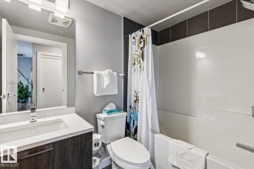 Bathroom featuring a vanity with an integrated sink, a wood-finish cabinet, and a large mirror - 3302 10180 103 Street, Edmonton, AB - Indoor Photo Showing Bathroom
