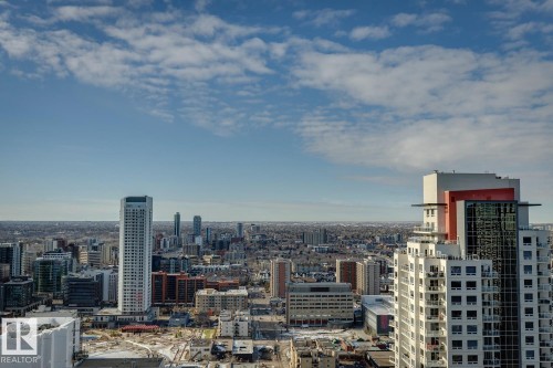 Expansive urban skyline featuring multiple high-rise buildings, a clear blue sky with scattered clouds, and distant low-rise residential areas - 3302 10180 103 Street, Edmonton, AB - Outdoor With View