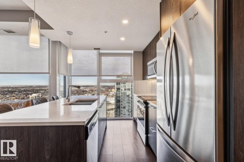 Modern kitchen featuring a large island with an undermount sink and two pendant lights - 3302 10180 103 Street, Edmonton, AB - Indoor Photo Showing Kitchen With Double Sink With Upgraded Kitchen