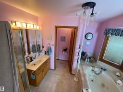 Bathroom featuring a built-in jetted tub, a vanity with dual sinks, and an adjacent shower enclosure - 