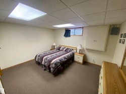 Carpeted room featuring a drop ceiling with integrated lighting, a built-in wall cabinet, and a window with blinds - 