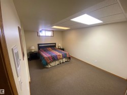 Spacious room featuring neutral carpeting, light-toned walls, and a drop ceiling with integrated lighting - 