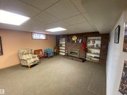 Spacious room featuring a brick-surround fireplace with a black hearth, built-in shelving, recessed lighting, and carpet flooring - 