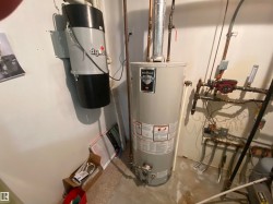 Utility area featuring a water heater, central vacuum system, concrete flooring, and exposed copper piping - 