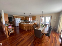 Open-concept kitchen and dining area featuring wood-finish flooring, light wood cabinetry, and a kitchen island with a light-toned countertop - 