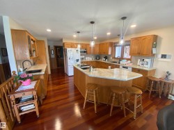 Spacious kitchen featuring warm wood cabinetry, light-toned countertops, and rich wood-finish flooring - 