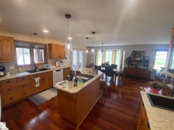 Spacious kitchen featuring a large island, wood-finish flooring, light-toned cabinetry, and integrated dining space - 