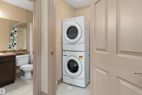 Dedicated laundry area featuring a stacked washer and dryer - 23 3103 Hilton Drive, Edmonton, AB - Indoor Photo Showing Laundry Room