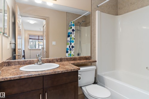 Bathroom vanity featuring a speckled countertop, integrated sink, and dark wood-finish cabinetry - 23 3103 Hilton Drive, Edmonton, AB - Indoor Photo Showing Bathroom
