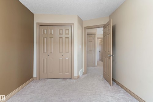 Neutral-toned room featuring a patterned carpet, bi-fold closet doors, and contrasting wall colors - 23 3103 Hilton Drive, Edmonton, AB - Indoor