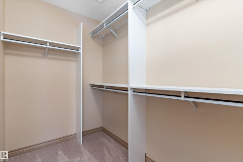Walk-in closet featuring light beige walls, carpet flooring, and white wire shelving with hanging rods - 23 3103 Hilton Drive, Edmonton, AB - Indoor With Storage