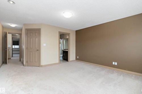 Spacious carpeted room featuring a neutral color palette with an accent wall, multiple doorways, and recessed lighting - 23 3103 Hilton Drive, Edmonton, AB - Indoor Photo Showing Other Room
