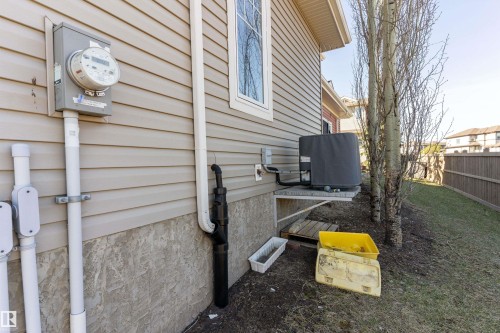 Property exterior featuring beige horizontal siding, a window with white trim, and a utility meter - 23 3103 Hilton Drive, Edmonton, AB - Outdoor With Exterior
