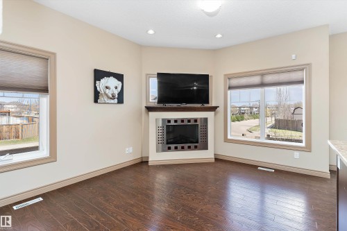 Corner fireplace with a stainless steel surround and wood-finish mantel - 23 3103 Hilton Drive, Edmonton, AB - Indoor Photo Showing Living Room With Fireplace