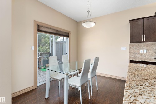 Dining area featuring wood-finish flooring, a contemporary pendant light fixture, and a sliding glass door providing outdoor access - 23 3103 Hilton Drive, Edmonton, AB - Indoor Photo Showing Dining Room