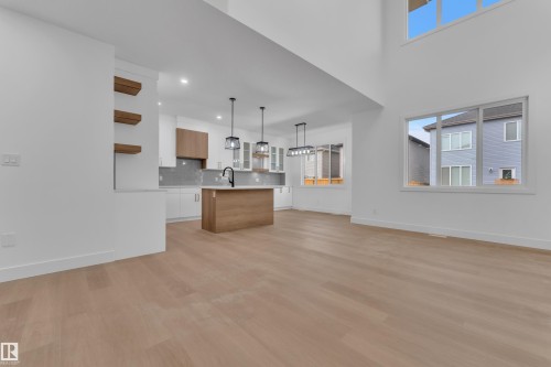 Open-concept living area featuring light wood-finish flooring, high ceilings, and abundant natural light from multiple windows - 6226 45 Avenue, Beaumont, AB - Indoor Photo Showing Kitchen