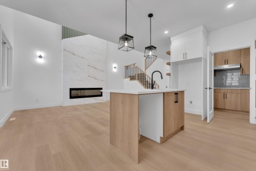 Open-concept living space with light wood-finish flooring - 6226 45 Avenue, Beaumont, AB - Indoor Photo Showing Kitchen With Fireplace