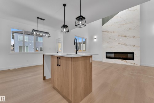 Kitchen island with an undermount sink, quartz countertop, and matte black faucet - 6226 45 Avenue, Beaumont, AB - Indoor With Fireplace