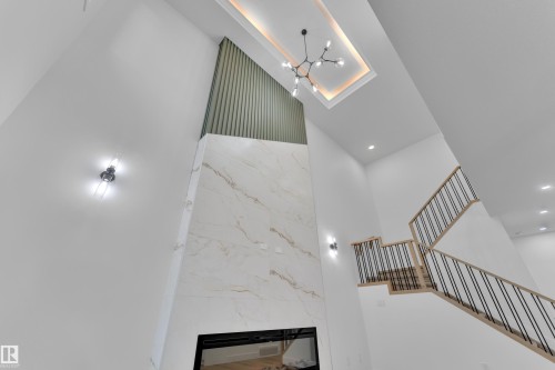Two-story fireplace with a wide electric insert, a marble-look facade, and a slatted accent wall - 6226 45 Avenue, Beaumont, AB - Indoor Photo Showing Other Room