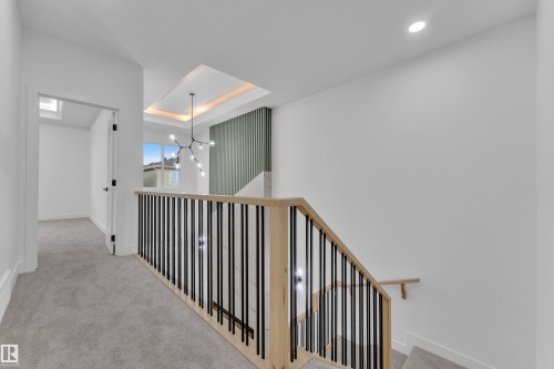 Modern staircase featuring light wood railings, black vertical balusters, and recessed ceiling lighting - 6226 45 Avenue, Beaumont, AB - Indoor Photo Showing Other Room