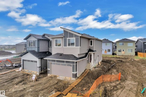 Modern architectural design featuring varied siding textures, a prominent front-facing garage, and a peaked roofline - 6226 45 Avenue, Beaumont, AB - Outdoor
