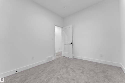 Minimalist interior room featuring soft gray carpet, white walls, and a white door with matte black hardware - 6226 45 Avenue, Beaumont, AB - Indoor Photo Showing Other Room