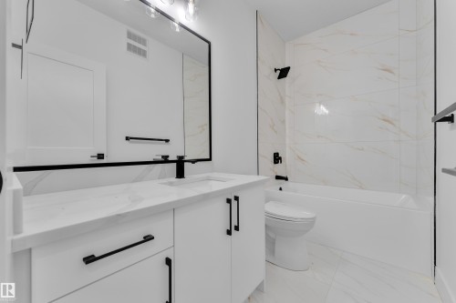 Bathroom featuring a white vanity with black hardware, an integrated rectangular sink, and a large framed mirror - 6226 45 Avenue, Beaumont, AB - Indoor Photo Showing Bathroom