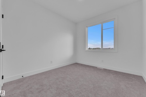 Neutral white walls with matching baseboards and trim, complemented by light gray carpet flooring - 6226 45 Avenue, Beaumont, AB - Indoor Photo Showing Other Room