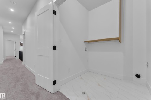 Dedicated laundry area featuring white tile flooring, a built-in wooden shelf, and connections for appliances - 6226 45 Avenue, Beaumont, AB - Indoor Photo Showing Other Room