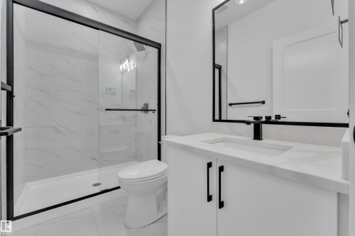 Bathroom featuring a glass-enclosed shower with black trim, a white vanity with a quartz-finish countertop, a rectangular undermount sink, and a black-framed mirror - 6226 45 Avenue, Beaumont, AB - Indoor Photo Showing Bathroom