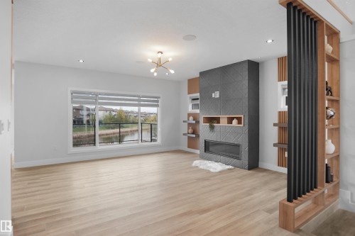 Living area featuring light wood-finish flooring and a contemporary linear fireplace with a textured tile surround - 162 Edgewater Circle, Leduc, AB - Indoor Photo Showing Living Room With Fireplace
